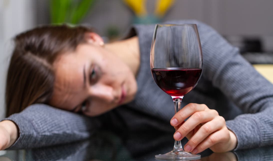lady with glass of wine crying alone at a table